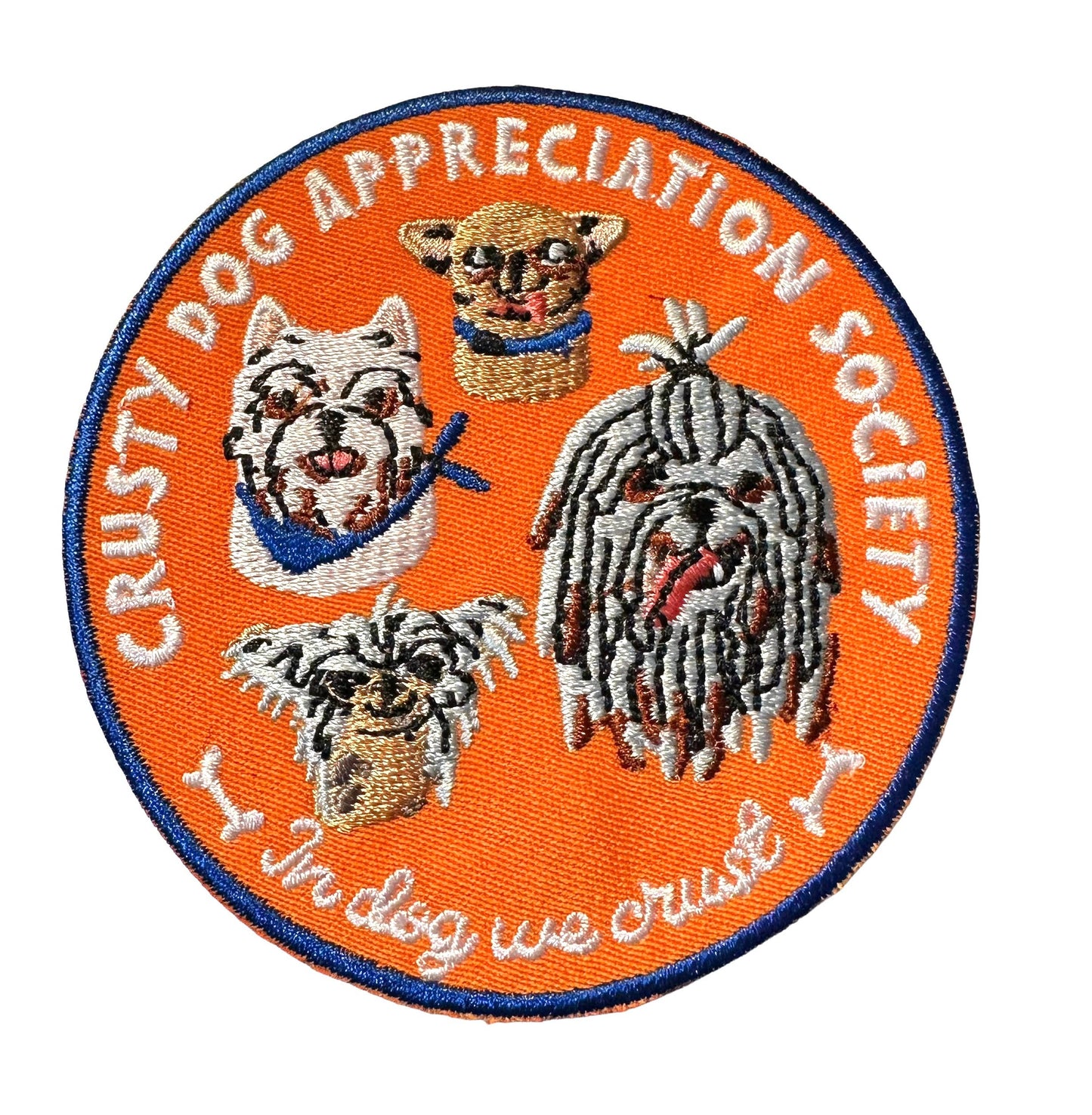 An embroidered oval patch for the 'Crusty Dog Appreciation Society' featuring four different dog breeds on an orange background with a blue border.