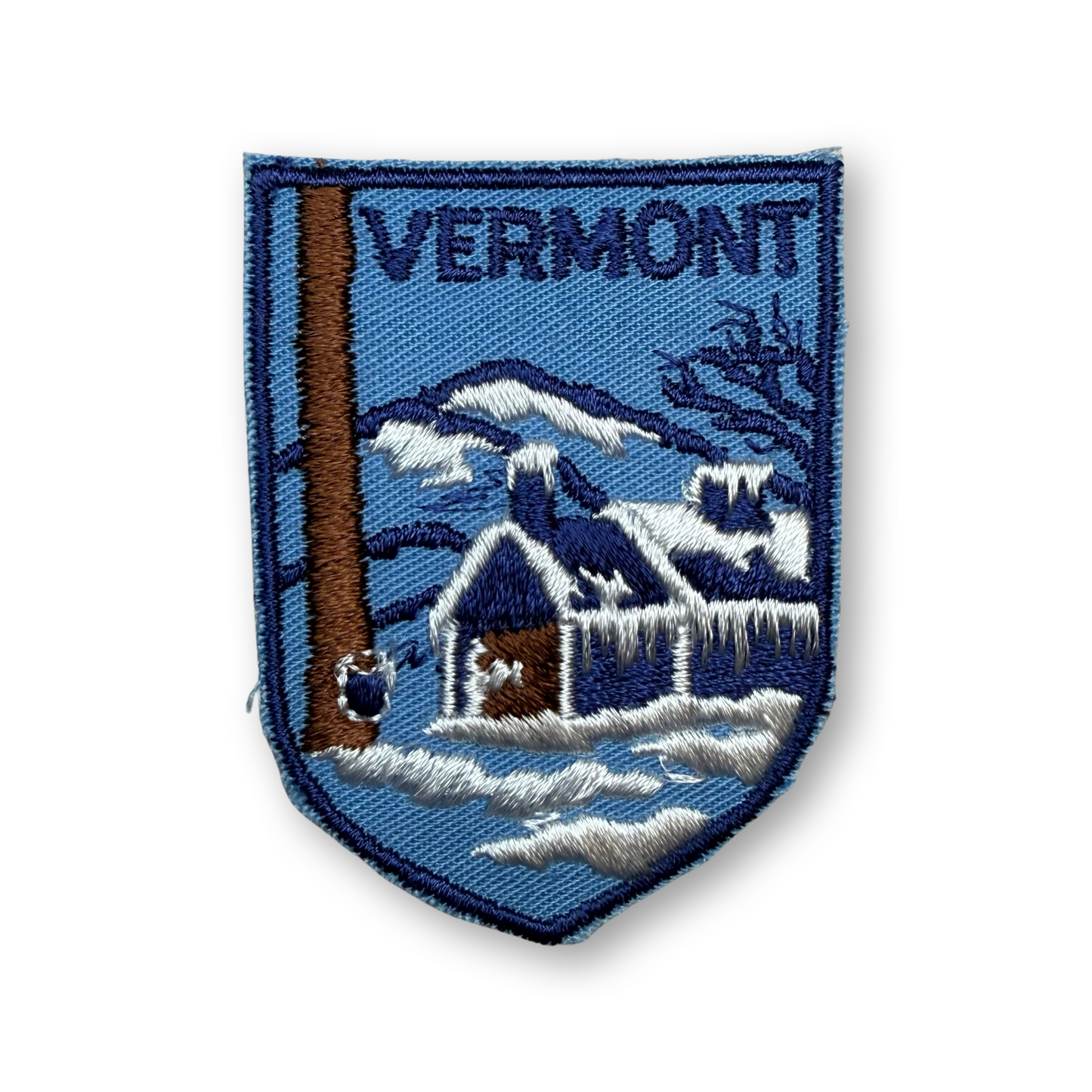 Vintage Vermont souvenir patch with a maple shack and trees embroidered on a blue background