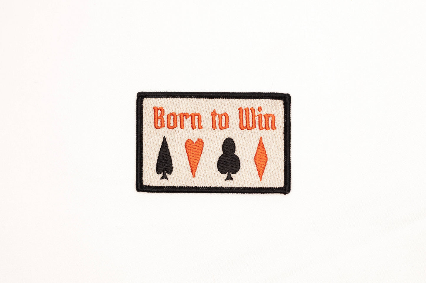 Patch with 'Born to Win' text and card suit symbols on a white background