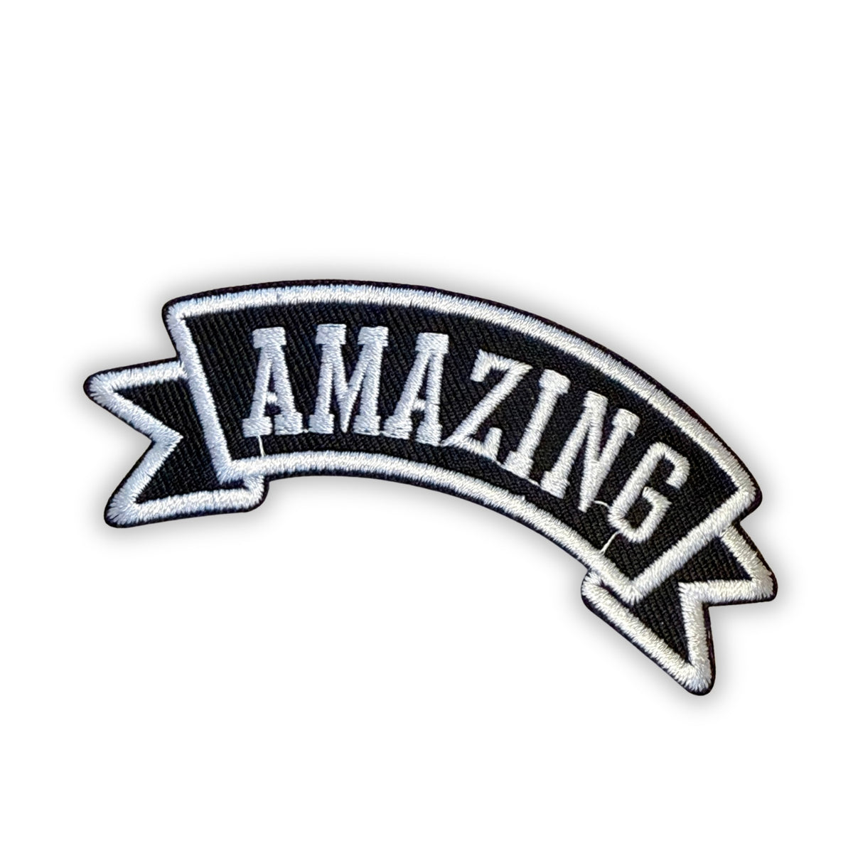 Black embroidered banner patch with white block letters spelling "AMAZING," arched with white-outlined swallowtail ends, on a white background.