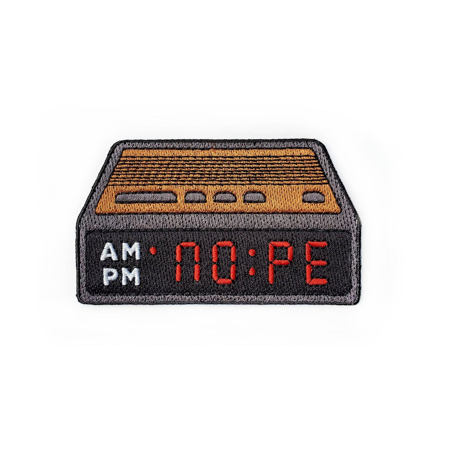 An embroidered patch shaped like a retro digital alarm clock, featuring a black body, a tan ribbed top, and red LED-style numbers showing 'NO:PE'. The left side displays 'AM' in white and 'PM' in gray.