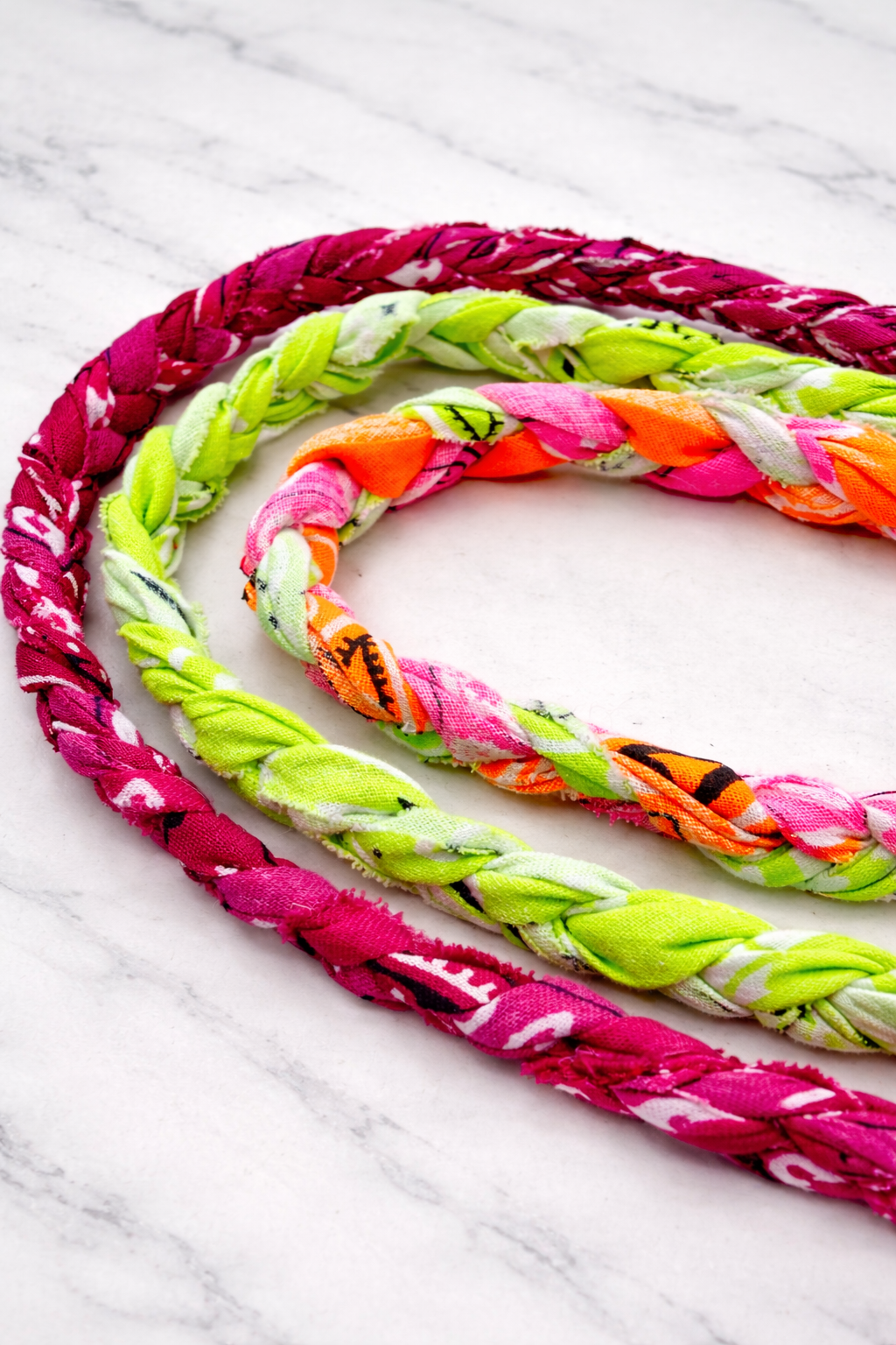 Colorful braided bandana necklaces on a marble surface