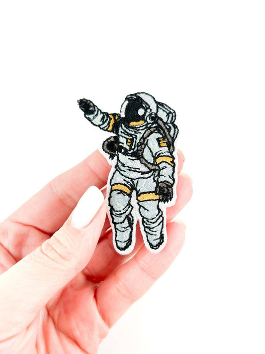 Hand holding an astronaut patch on a white background