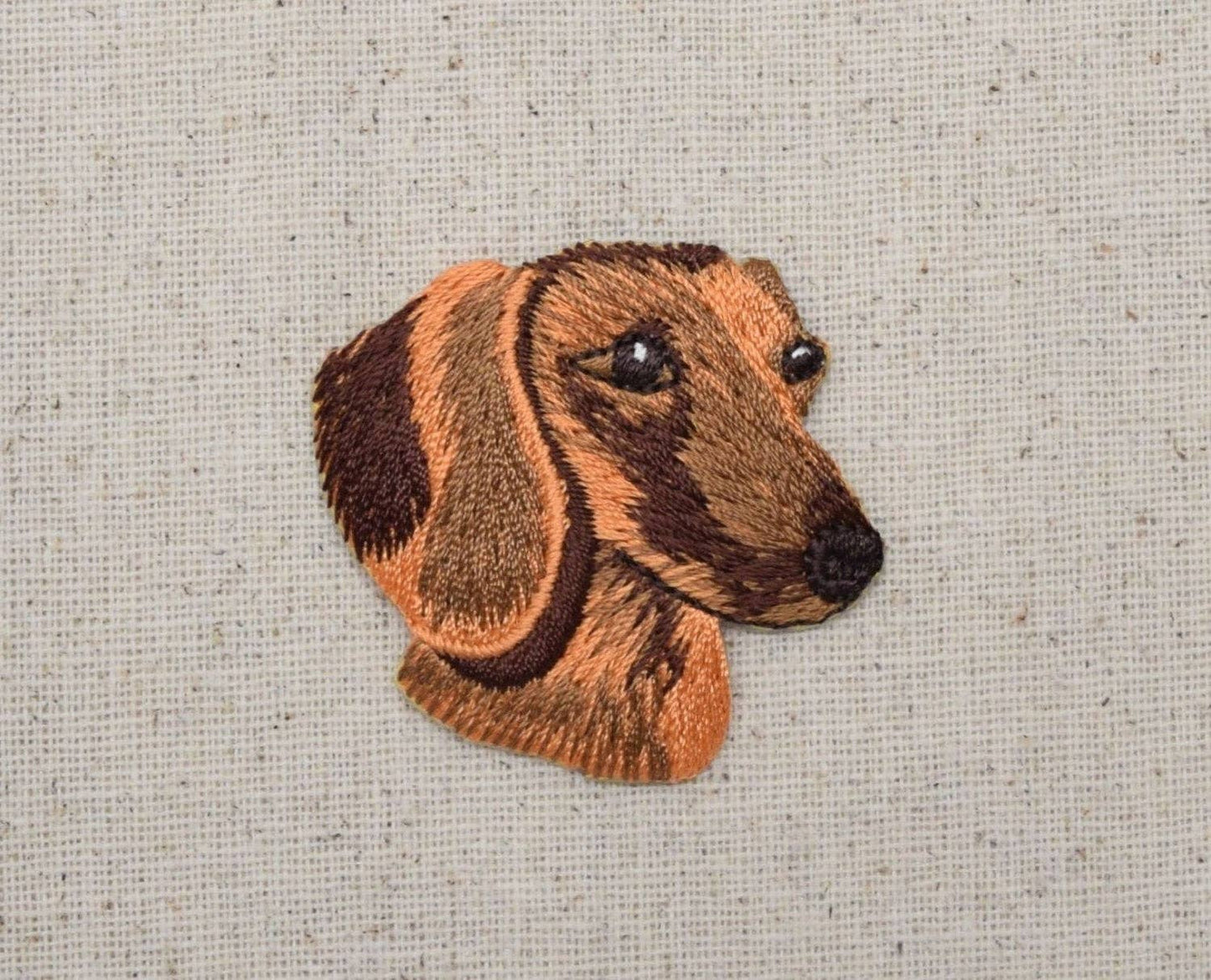 Embroidered patch of a dachshund's head on a textured fabric background