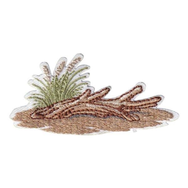 Embroidered patch of driftwood on beach with sea grass with a white background