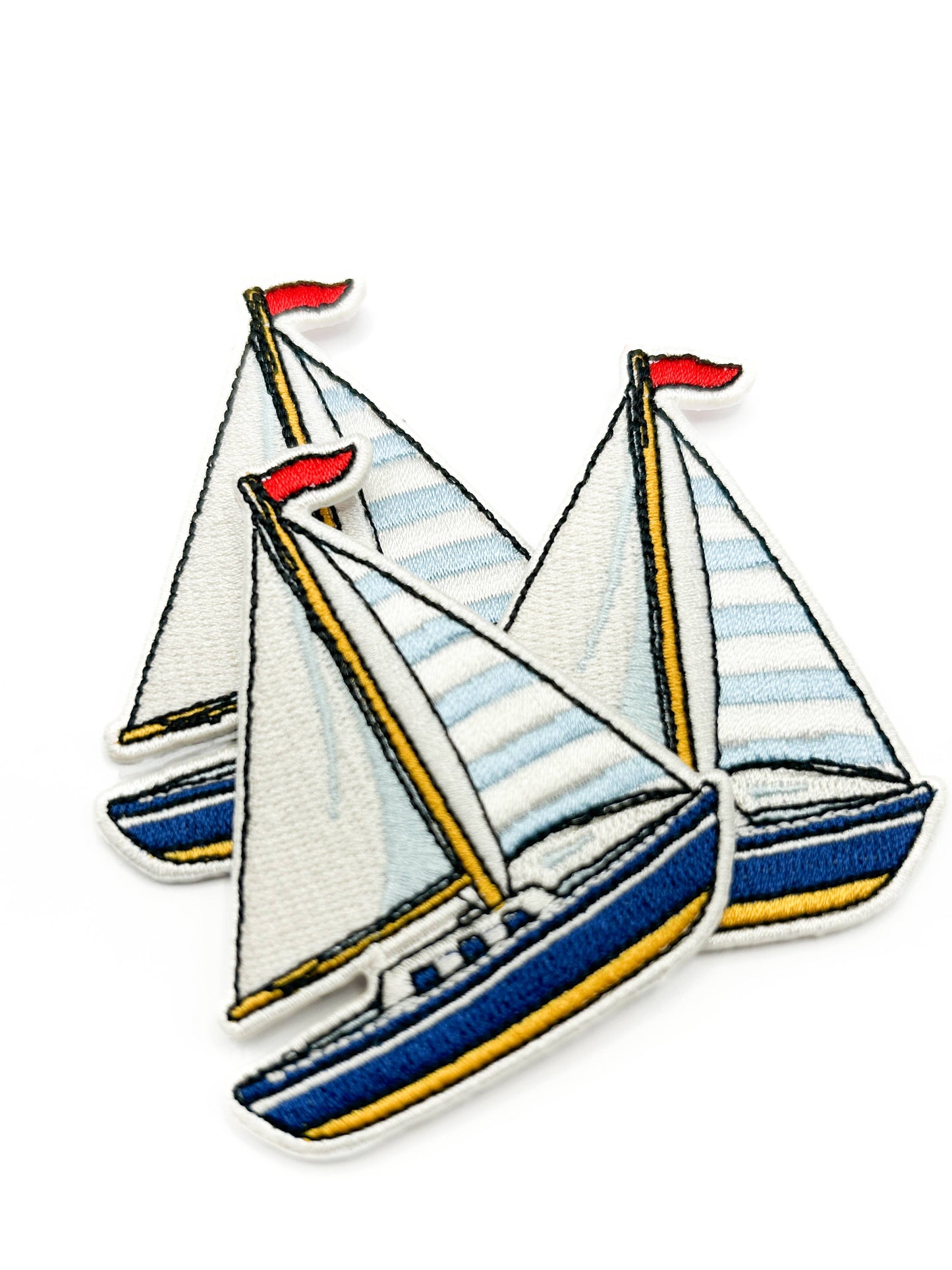 Three sailboat patches with striped sails on a white background