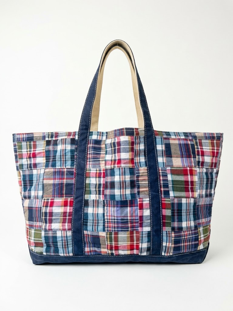 Vintage L.L. Bean patchwork madras canvas weekender tote bag, large size, with red blue green plaid pattern and navy handles isolated on white.