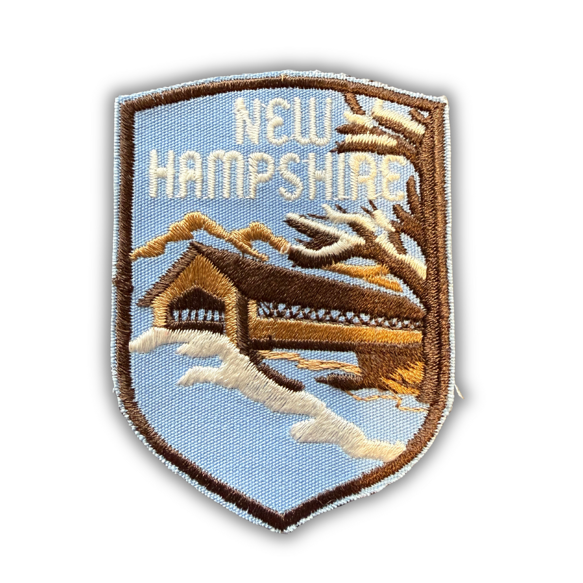 Vintage New Hampshire embroidered shield patch, snowy covered bridge and mountains, brown and light blue