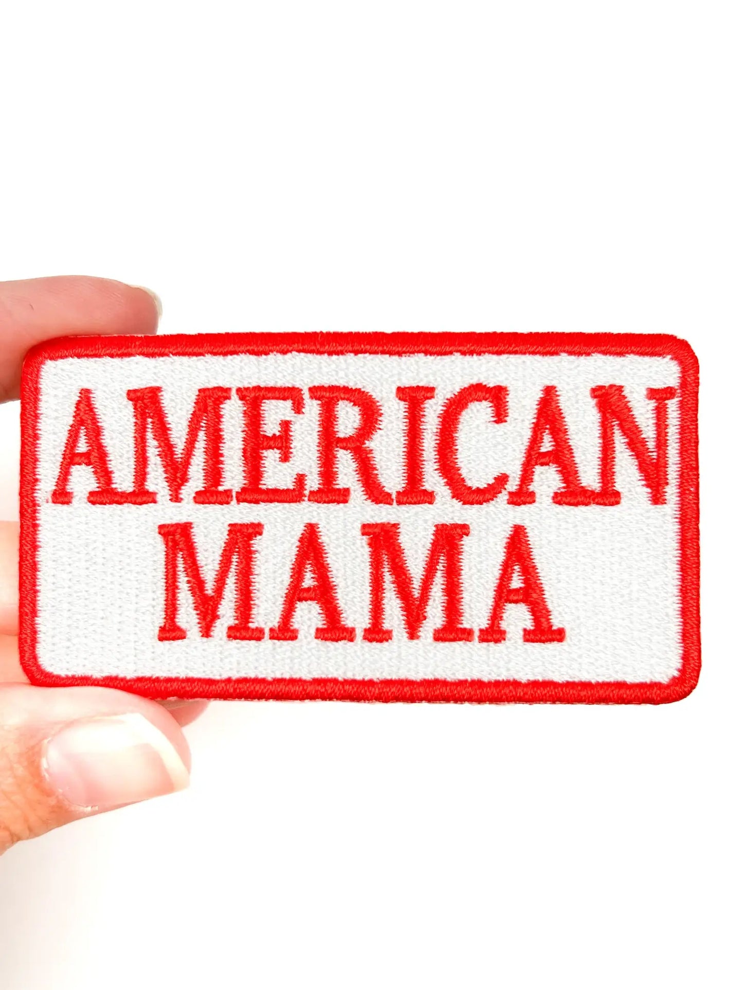 Embroidered patch with 'AMERICAN MAMA' text held by a hand on a white background