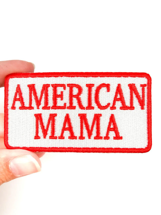 Embroidered patch with 'AMERICAN MAMA' text held by a hand on a white background