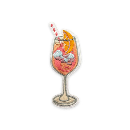 Embroidered patch of a cocktail glass with a straw and orange slice on a white background