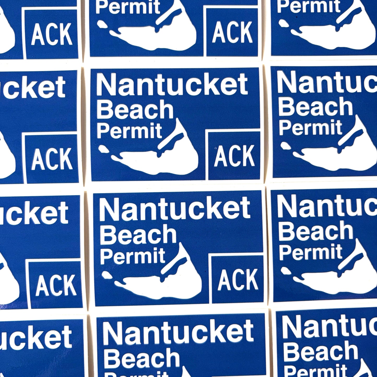 A close-up grid of identical blue and white Nantucket Beach Permit stickers, each showing the island silhouette and the text 'Nantucket Beach Permit' with 'ACK' in a blue box.