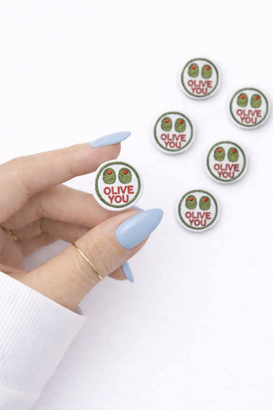 Hand holding a set of 'OLIVE YOU' stickers on a white background