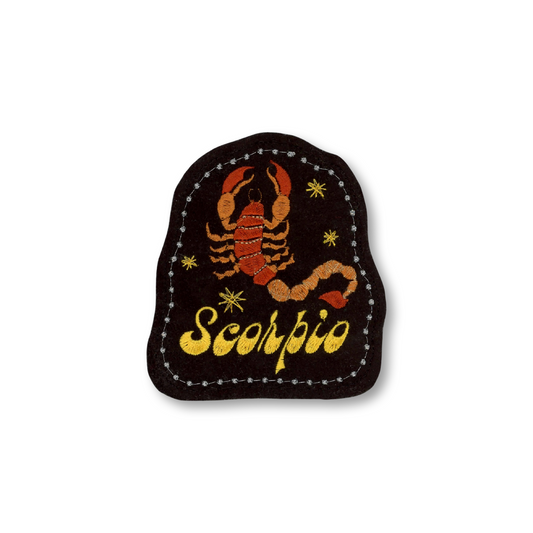 A black embroidered patch featuring a red and orange scorpion design with the word 'Scorpio' in yellow script, surrounded by small yellow stars and a dotted stitched border, shown on a plain white background.