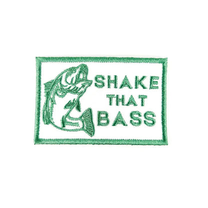 A rectangular embroidered patch with a green border, featuring a green fish illustration on the left and the text 'SHAKE THAT BASS' in green on a white background.