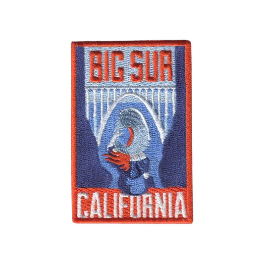 An embroidered rectangular patch featuring the words 'BIG SUR' at the top and 'CALIFORNIA' at the bottom, with a stylized blue and white bridge and red-orange accents in the center, shown on a plain white background.