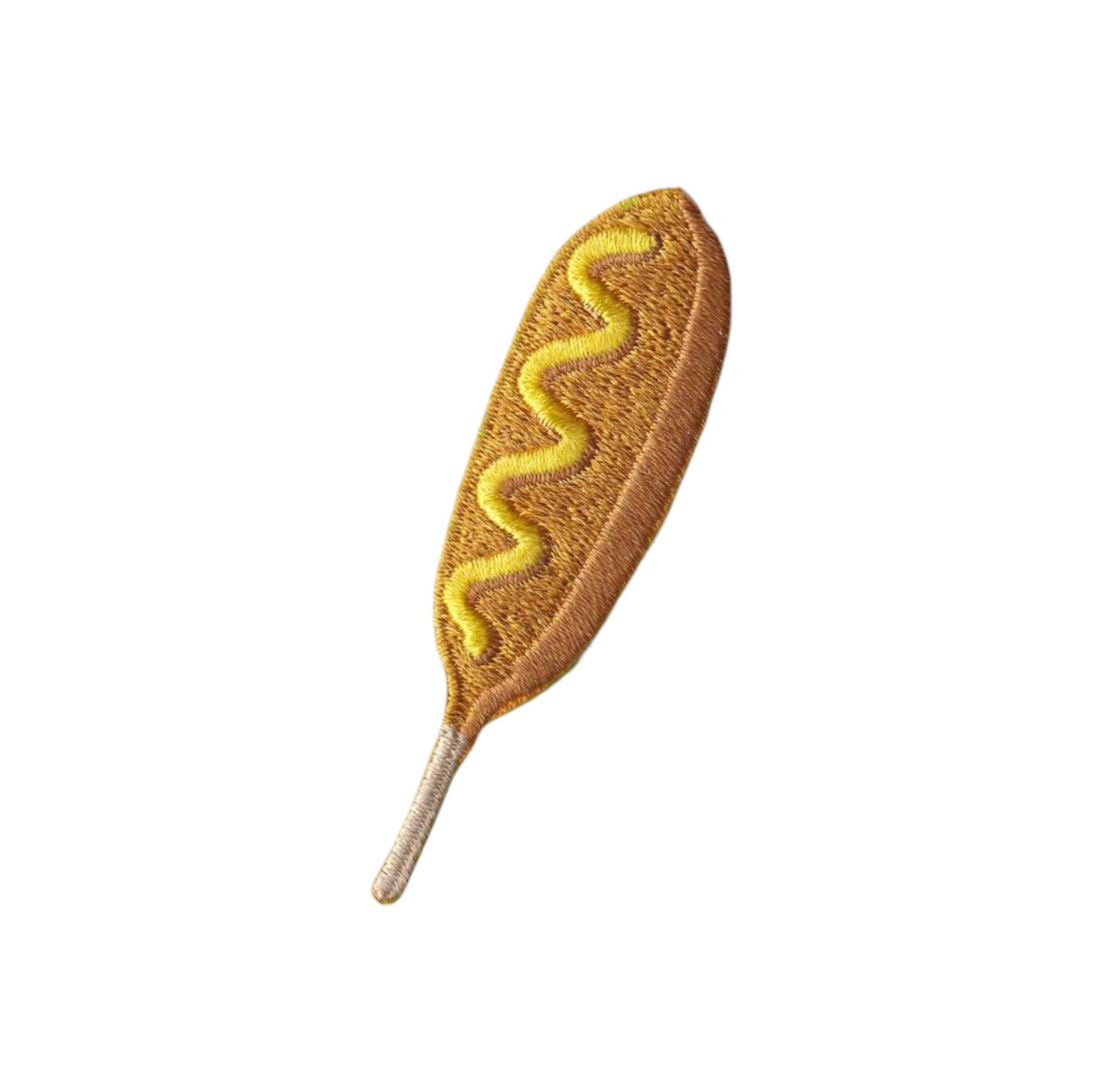 An embroidered patch shaped like a hot dog, featuring a golden-brown textured body with a zigzag yellow mustard line and a light beige stem, isolated on a white background.