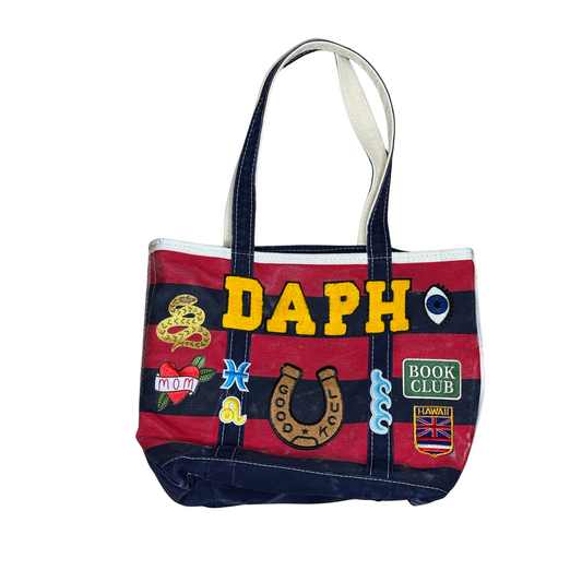 Tote bag with various patches and the name 'DAPH' on a white background