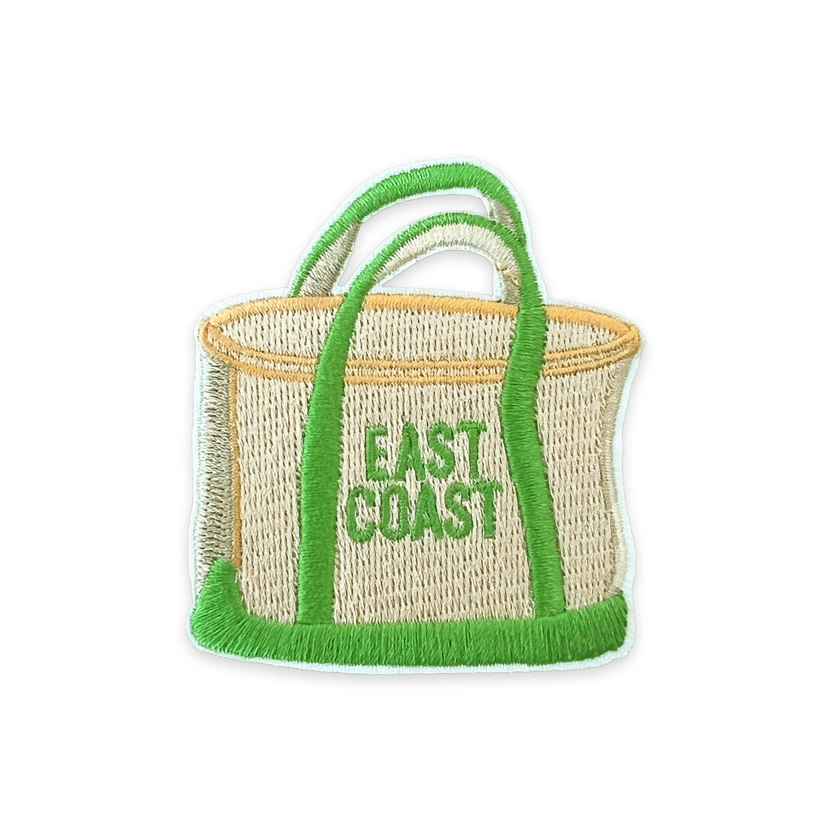 A woven straw tote bag with bright green handles, trim, and fringe, featuring the words 'EAST COAST' embroidered in green on the front, isolated on a white background.