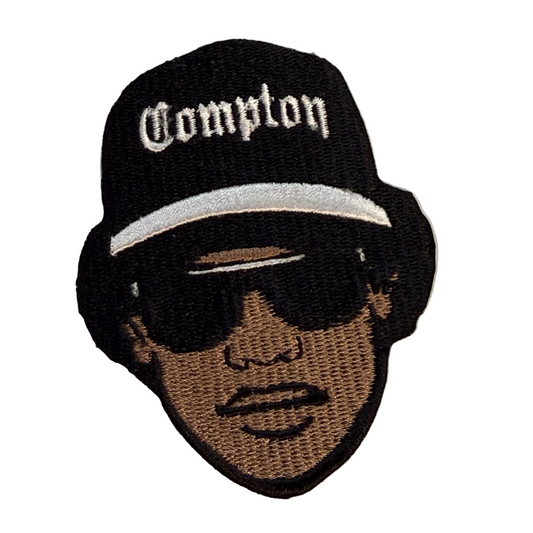 Embroidered patch of a person wearing a 'Compton' hat on a white background