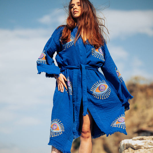 Woman wearing a blue embroidered robe against a natural background