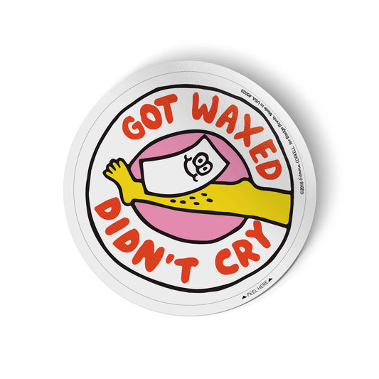 A circular novelty sticker with a white border and a cartoon illustration of a yellow arm wrapped in pink wax paper with a crying face. The text reads 'GOT WAXED DON'T CRY' in red-orange lettering.