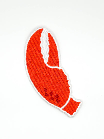 An embroidered lobster claw patch in bright red-orange with a white border, shown on a plain white background.