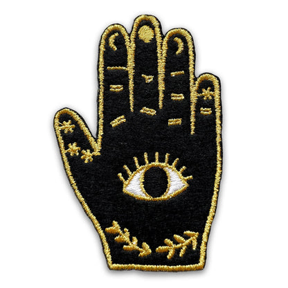 Embroidered patch of a palm with an eye design on a black background
