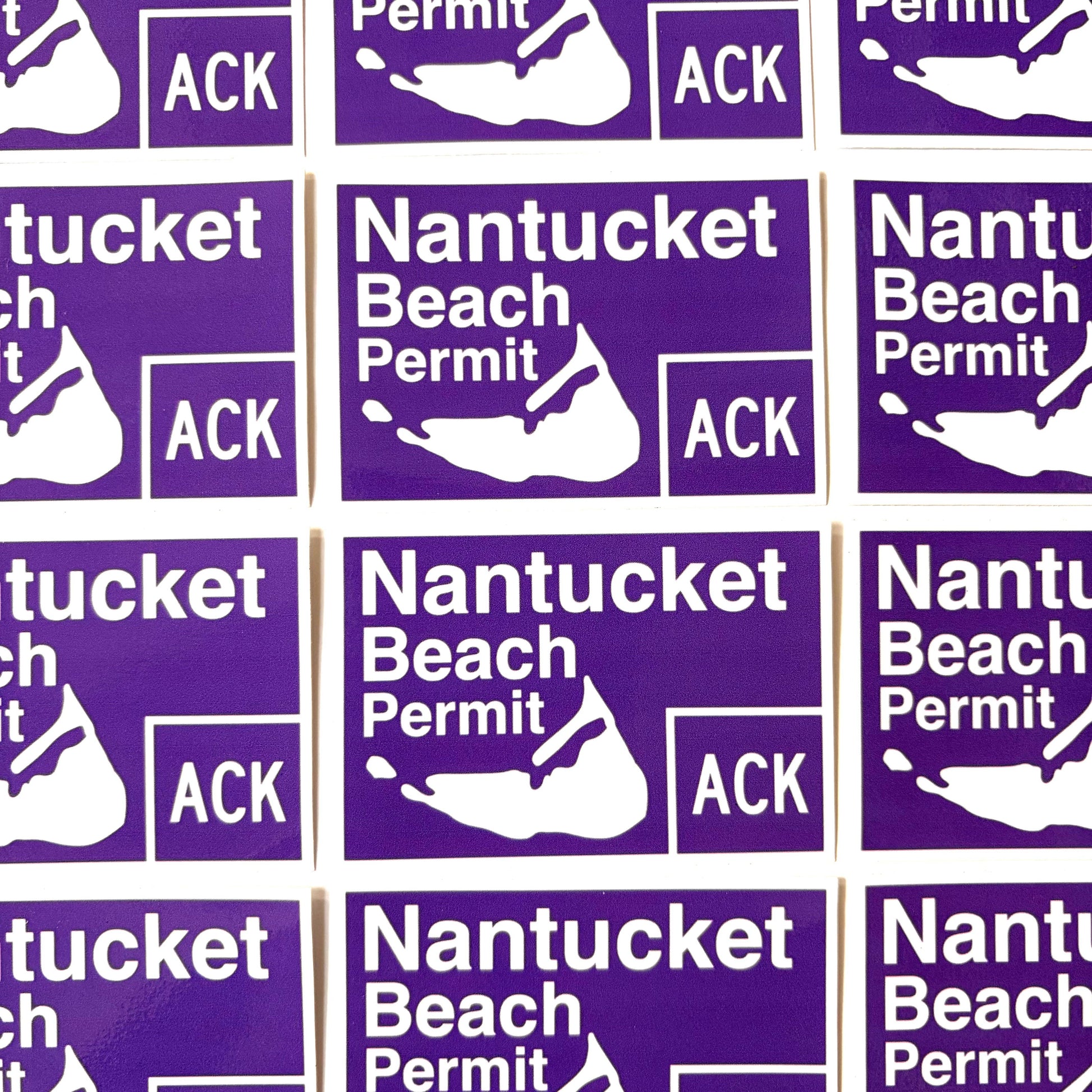 A close-up grid of purple rectangular stickers with white text reading 'Nantucket Beach Permit' and a white silhouette of Nantucket Island, with 'ACK' in a box to the right.