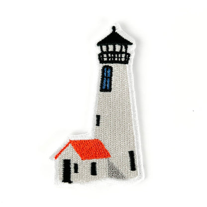 Knitted lighthouse with a small house on a white background