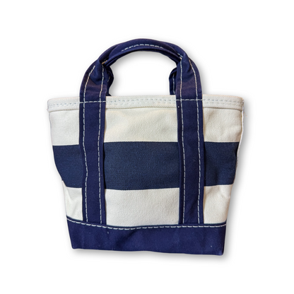 A small canvas tote bag with horizontal navy blue and off-white stripes, featuring thick navy handles and white contrast stitching, shown on a plain white background.