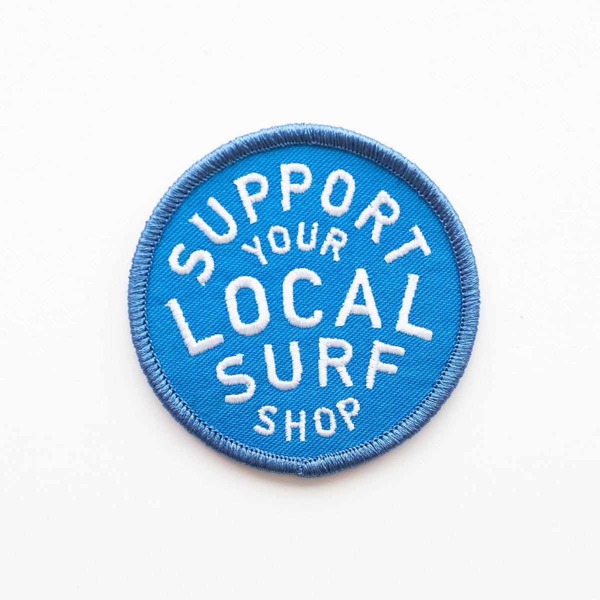 Blue patch with white text 'Support Your Local Surf Shop' on a white background