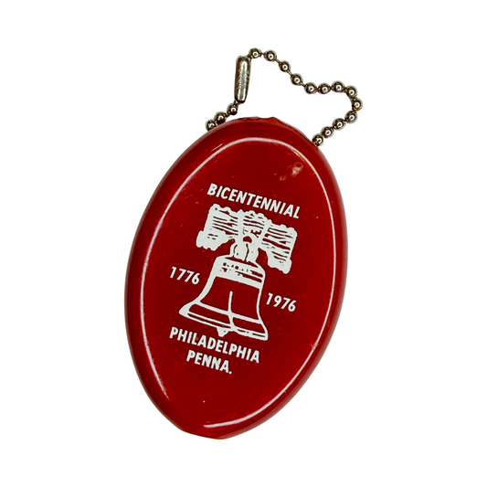 Red vintage rubber squeeze coin purse keychain with white Liberty Bell graphic, Bicentennial text, dates 1776 and 1976, and Philadelphia Penna. inscription on white background