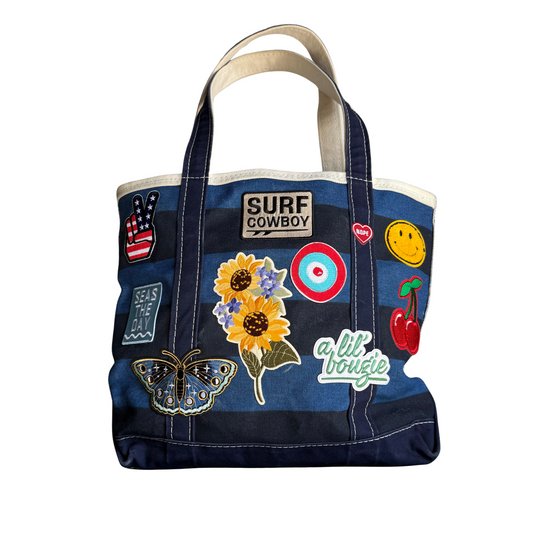 Blue tote bag with various patches and designs on a white background