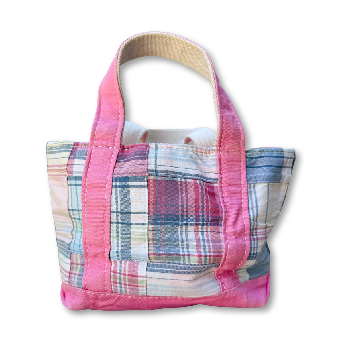 A small fabric tote bag with a pink and blue plaid patchwork design, featuring solid pink handles and trim, shown against a plain white background.