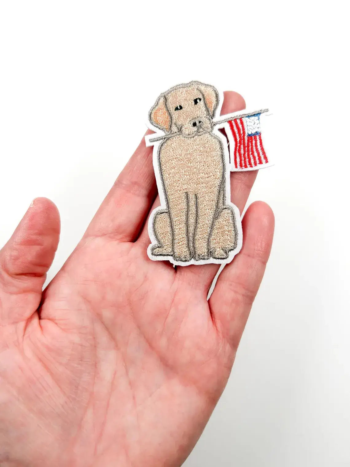 Sticker of a dog holding an American flag on a hand against a white background