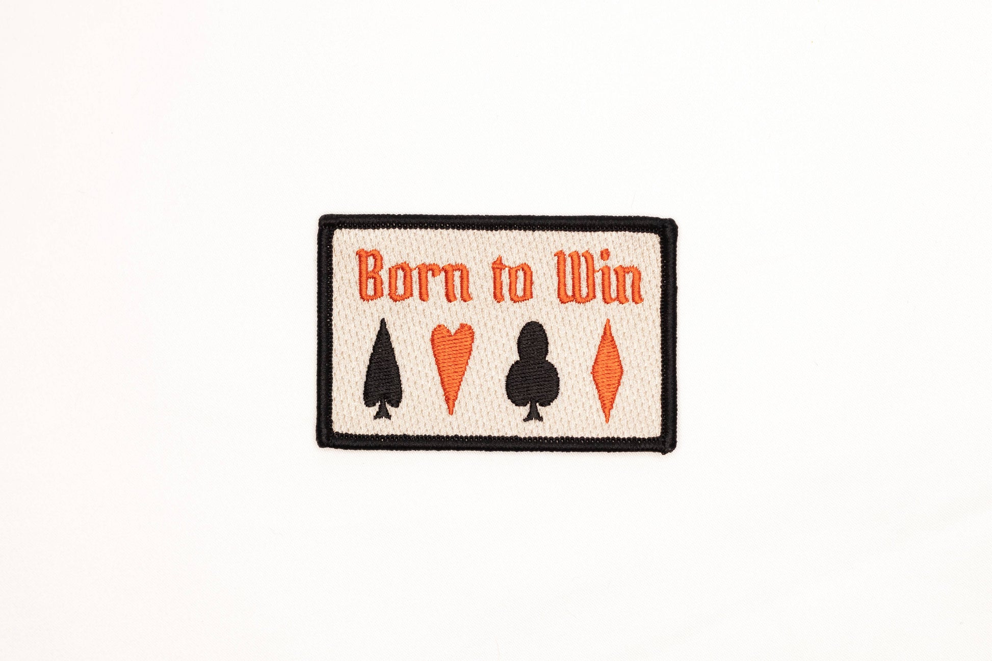 Patch with 'Born to Win' text and card suit symbols on a white background
