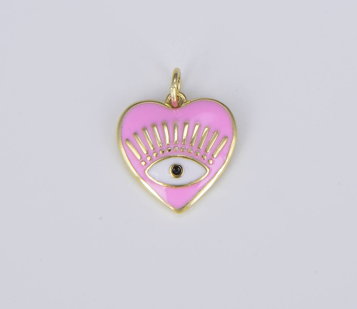 Pink heart-shaped pendant with gold accents and a black eye symbol on a light gray background