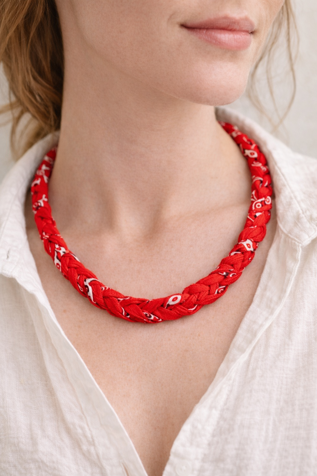 Red braided necklace worn by a person with a white shirt