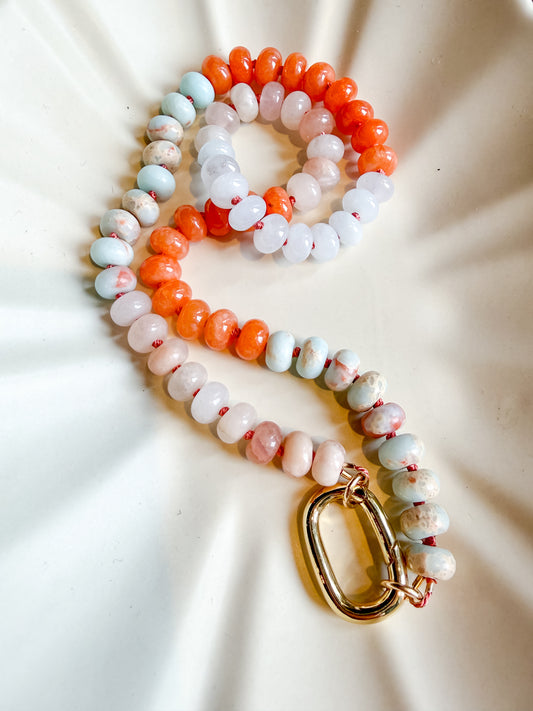 aqua terra jasper Beaded necklace with a gold clasp on a textured beige surface