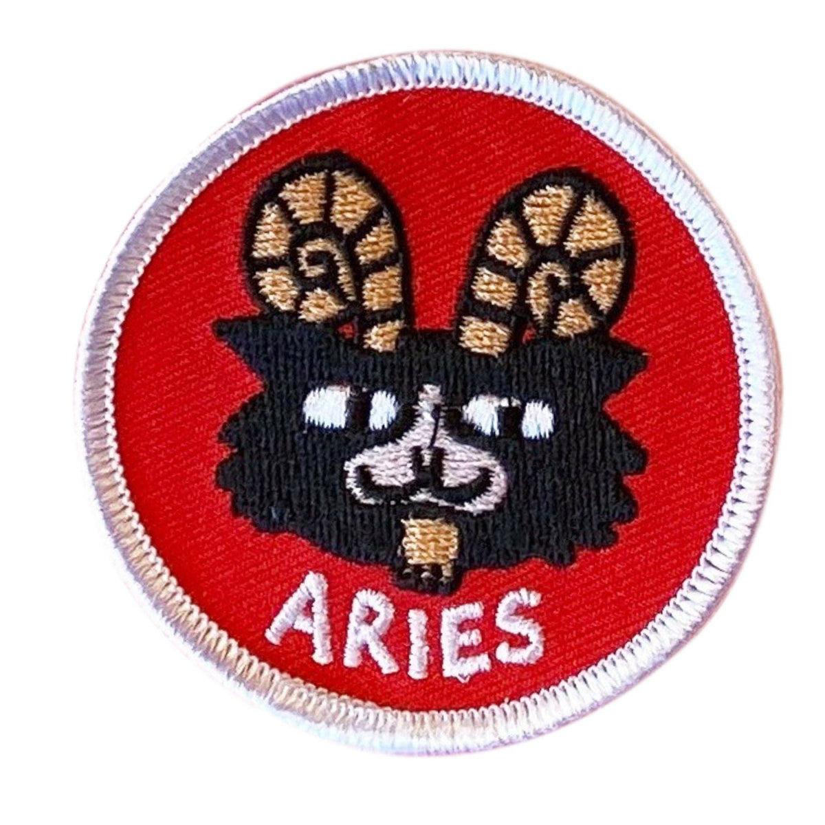 A circular embroidered patch featuring a black goat head with tan-brown horns and the word 'aries' in white at the bottom, on a red background with a white stitched border.