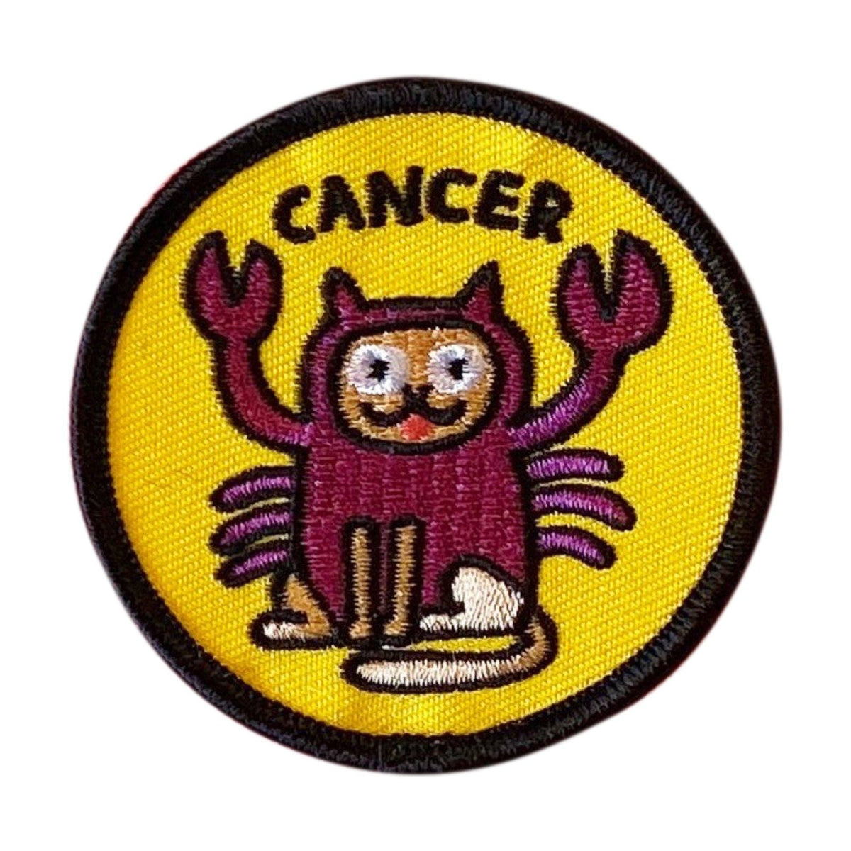 A circular embroidered patch featuring a cartoon crab character with the word 'CANCER' above it, on a bright yellow background with a black stitched border.