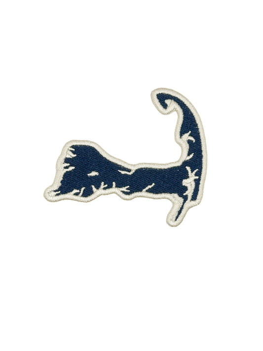 An embroidered patch shaped like the Cape Codic seal, featuring a navy blue design with a white embroidered border on a solid white background.