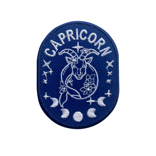 Capricorn zodiac patch with blue border and white design on a white background