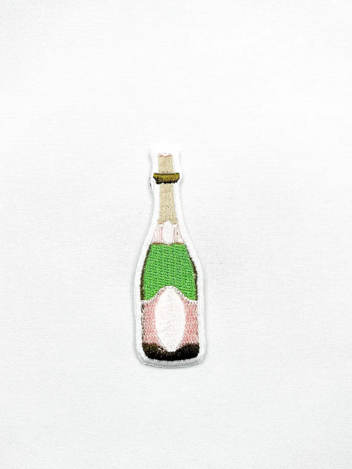 Knitted patch of a champagne bottle on a white background