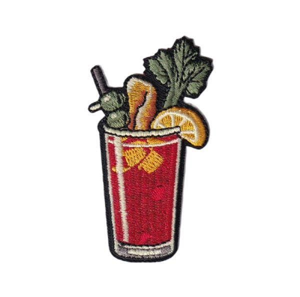 Embroidered patch of a Bloody Mary with a red drink, celery, and lemon on a white background