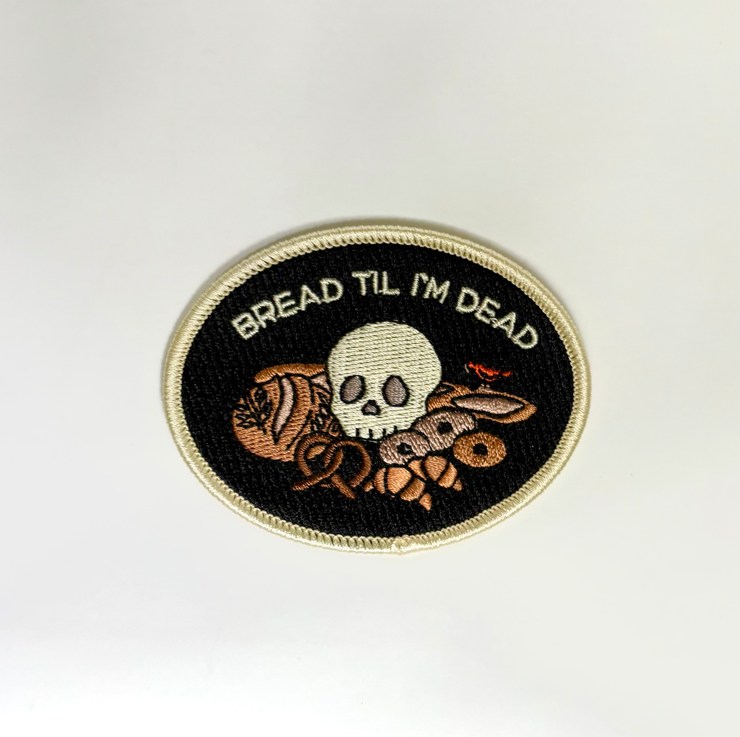 Embroidered patch with skull and bread design on a white background
