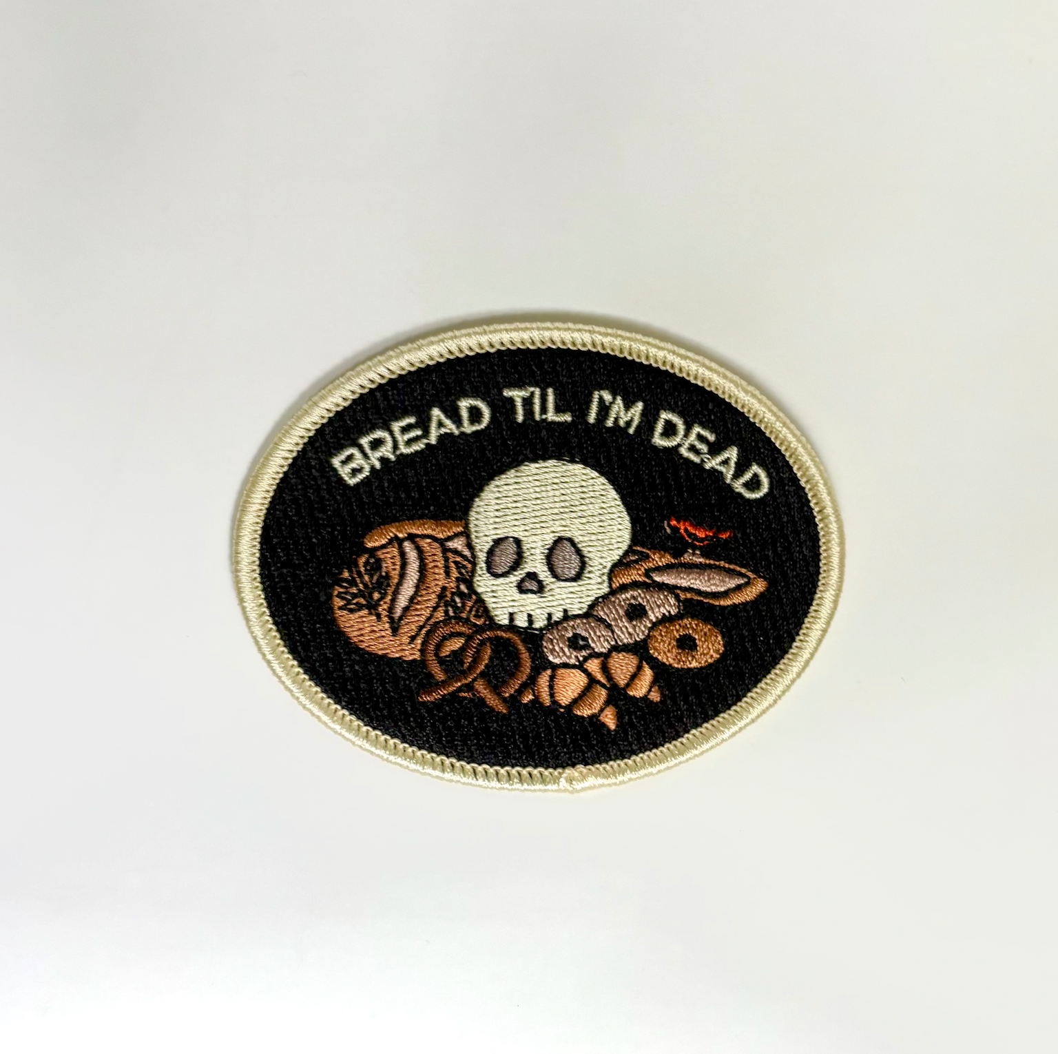Embroidered patch with skull and bread design on a white background