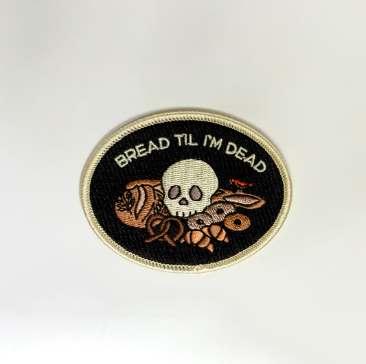 Embroidered patch with skull and bread design on a white background
