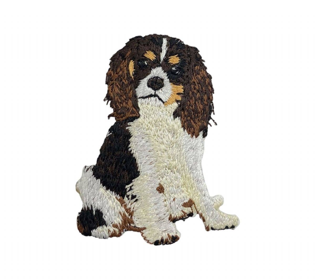 Embroidered patch of a tricolor dog on a white background